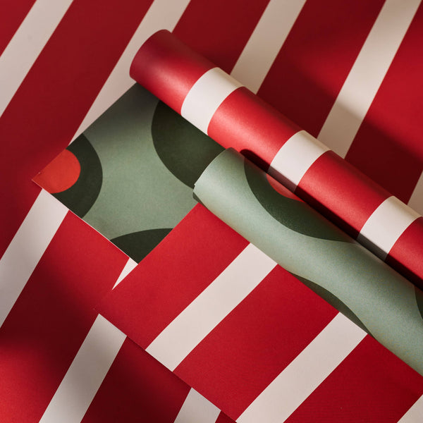 Two rolls of red and green striped paper on a red background with white stripes.