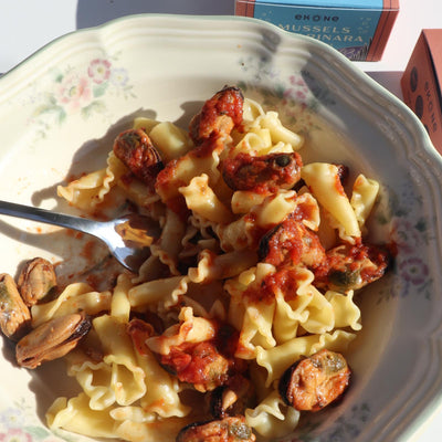 Pasta dish with mussels and tomatoes on a floral-patterned plate
