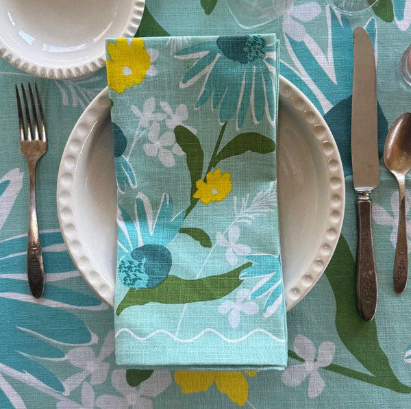 Floral-patterned napkin on a table setting with plates, cutlery, and a colorful tablecloth.