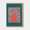 Greeting card with floral design and red vase silhouette on teal background