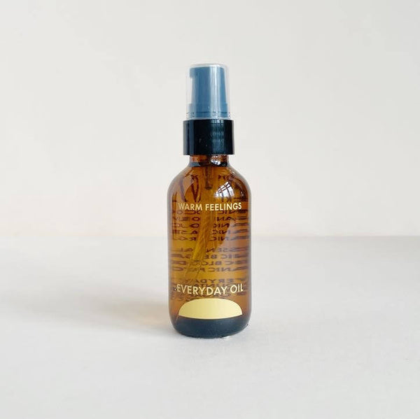 A brown glass bottle labeled "Warm Feelings" branded with "Everyday Oil" against a neutral background.