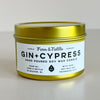 Gold tin candle labeled 'Gin + Cypress' by Fern & Nettle on a light gray background