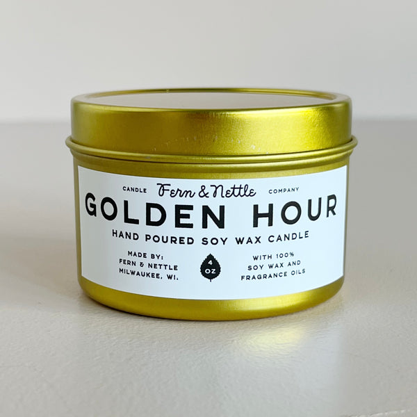 Candle in a gold tin with a white Golden Hour label on a light gray background