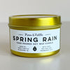 Gold candle tin labeled 'Spring Rain' by Fern & Nettle on a light background