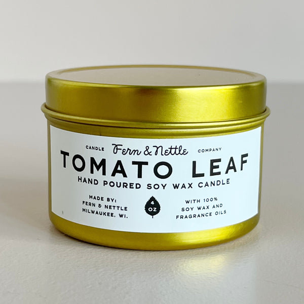 Gold candle jar with 'Tomato Leaf' label on a light background