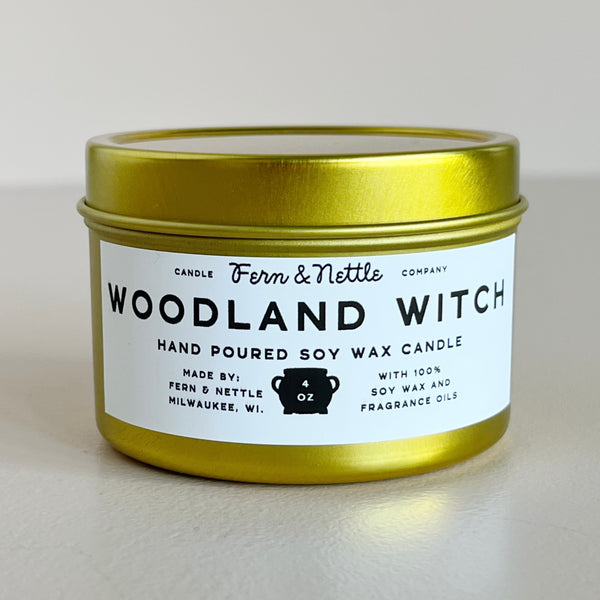 Gold candle tin with 'Woodland Witch' label on a light background