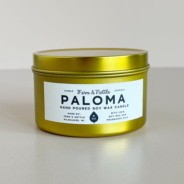 Gold candle jar with 'Paloma' label on a light background