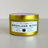 Gold candle tin labeled 'Woodland Witch' on a light background