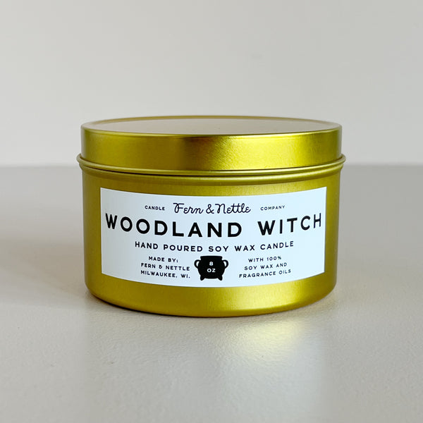 Gold candle tin labeled 'Woodland Witch' on a light background