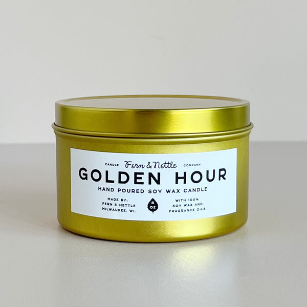 Gold candle tin labeled 'Golden Hour' by Fern & Nettle on a light background