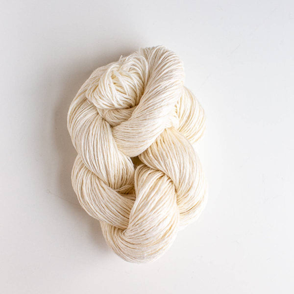 Ivory-colored skein of linen yarn on a light gray background