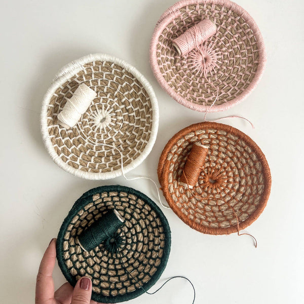 Four woven baskets with yarn on a light background.