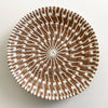 Woven basket with brown and white pattern on a light gray background