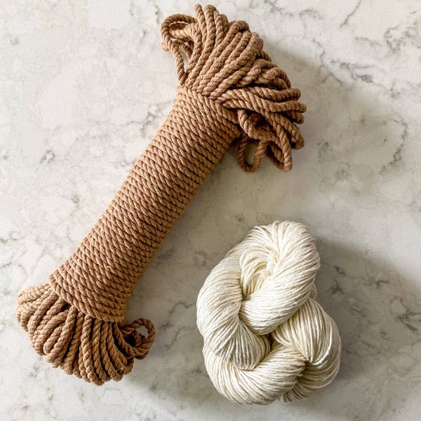 Brown rope and white skein of yarn on a marble surface