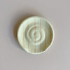Round ceramic spoon rest with rust orange stripes on a neutral background
