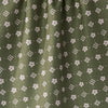 Close-up of olive green tea towel with a repeating white floral and geometric pattern.