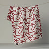 A white kitchen towel with a red bow pattern hanging from a white, revealing the reverse side in the same print in a reverse colorway, photographed against a neutral backdrop.