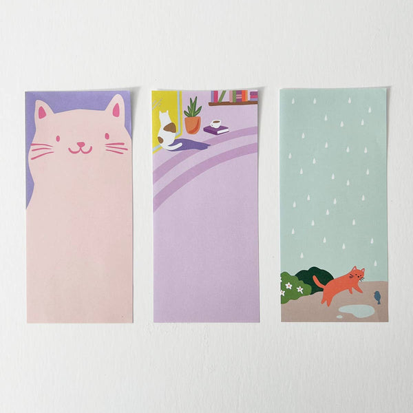 Three illustrated notepads featuring cats and a plant on a white background