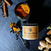 A jar of 'Golden Milk' with turmeric and spice mix, alongside cinnamon sticks, ginger, and cardamom pods.