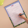 Person writing in a colorful monthly planner for the month of April on a beige surface