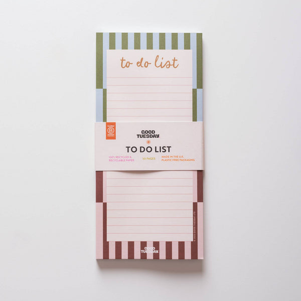 A to-do list pad by Good Tuesday featuring a contrasting stripe design in blue and green on the top and maroon and peach on the bottom, photographed on a white backdrop.