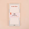A vertical to-do list notepad with a white paper band around the middle, featuring pastel blue and cream stripes and the words 'to do list' at the top, photographed on a solid beige background.