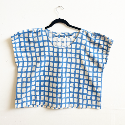 Blue and white checkered top on a hanger against a white background