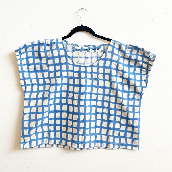 Blue and white checkered top on a hanger against a white background