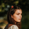 Woman with a mini wildflower hair  claw holding back the front of her hair against a blurred natural background