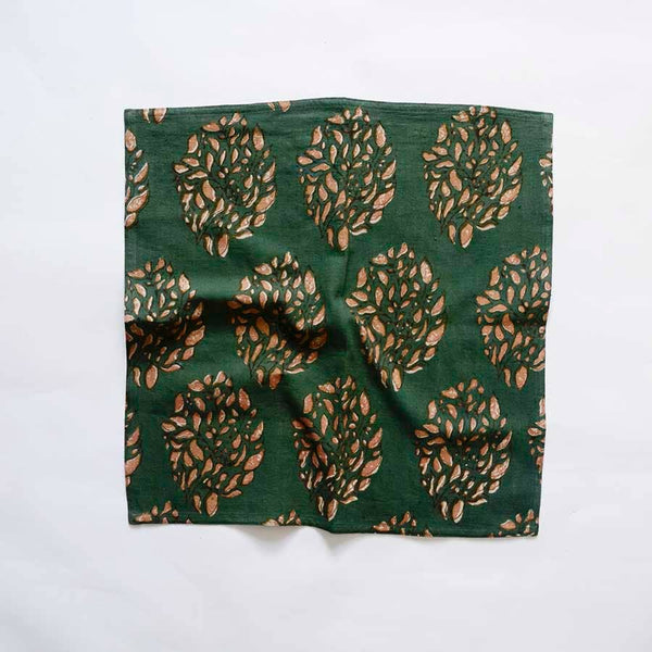 A dark green and warm orange-brown patterned cotton napkin scrunched up on a white backdrop.