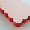Detail of pink scalloped notepad with a bright red edge on a white background.