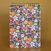 Spiral top notebook with a colorful floral pattern on a brown background