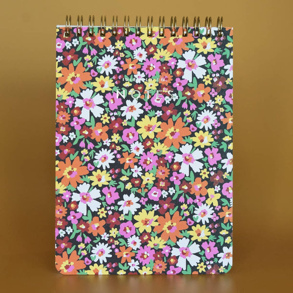 Spiral top notebook with a colorful floral pattern on a brown background