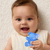 Baby holding a blue teddy bear-shaped teether against a neutral background