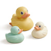 Three rubber ducks in yellow, green, and white on a white background