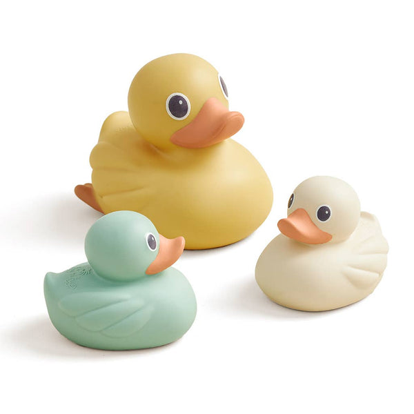 Three rubber ducks in yellow, green, and white on a white background