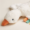 White plush toy goose with an orange beak on a beige background