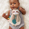 Baby holding a plush sloth toy on a white fluffy surface