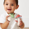 Child holding two colorful mushroom shaped maraca toys against a plain background