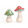 Two mushroom-shaped maraca toys with smiling faces on a white background