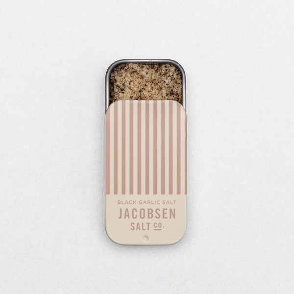 Tin of Jacobsen Salt Co. black garlic salt on a light gray background