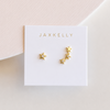 Gold star earrings with delicate white CZ stones on a Jaxkelly branded card against a light pink background