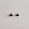 Pair of triangle-shaped black tourmaline gemstone earrings with gold settings on a light gray background