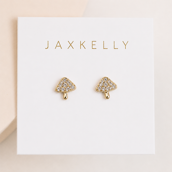Tiny gold mushroom-shaped earrings with CZ pave studs on a Jaxkelly branded card.