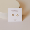 Gold and white opal stud earrings on a Jaxkelley branded card with a beige background