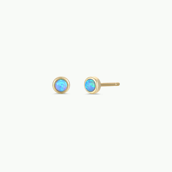 Pair of gold earrings with fire opal gemstones on a white background