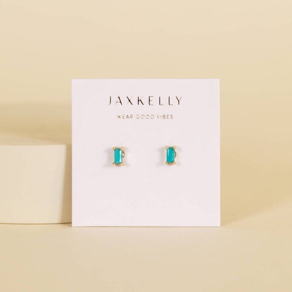 JAXKELLY turquoise and gold baguette stud earrings on a display card with a beige background