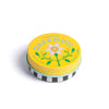 Tin of lip balm with yellow lid featuring a daffodil design on a white background