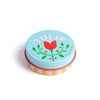 Tin of lip balm with a tulip design on the lid against a white background