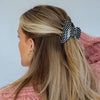 Woman with blonde hair held half up with a black and white polka dot claw clip.